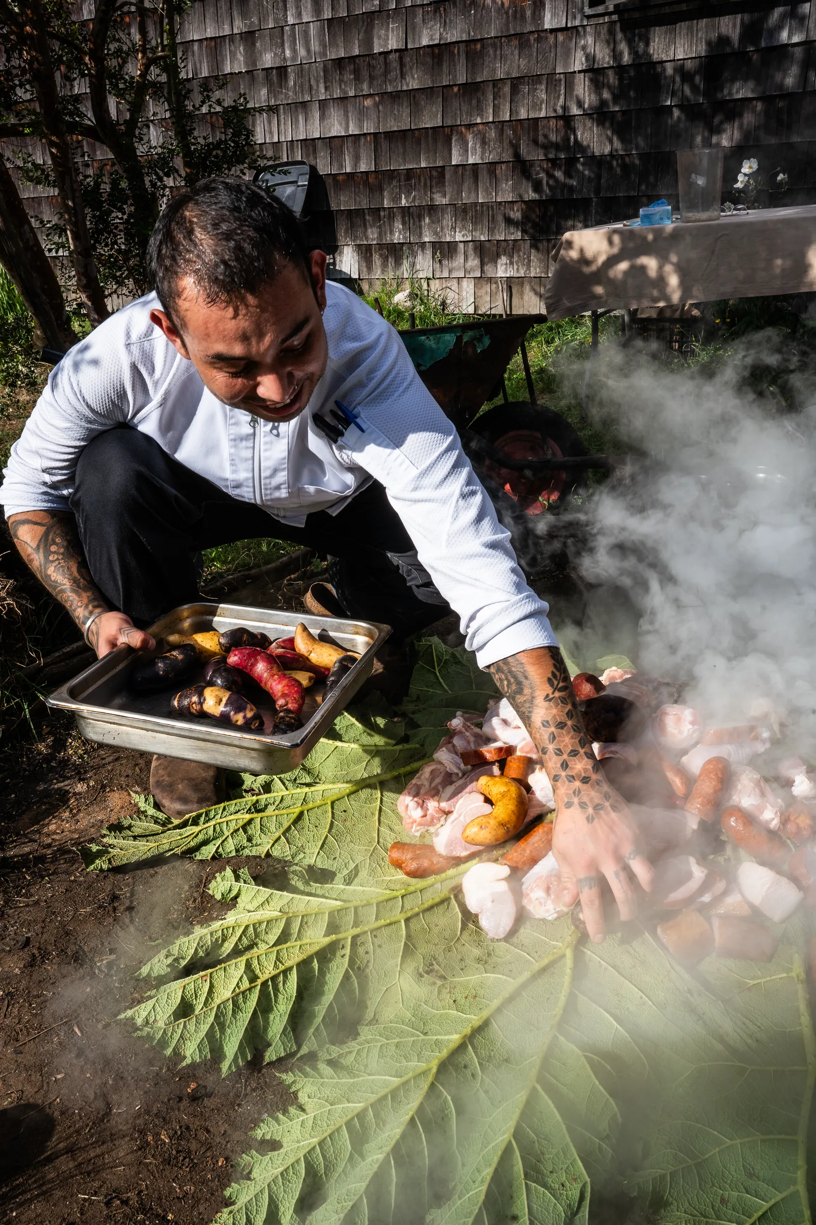 A chef preparing food over native leaves in Chiloé