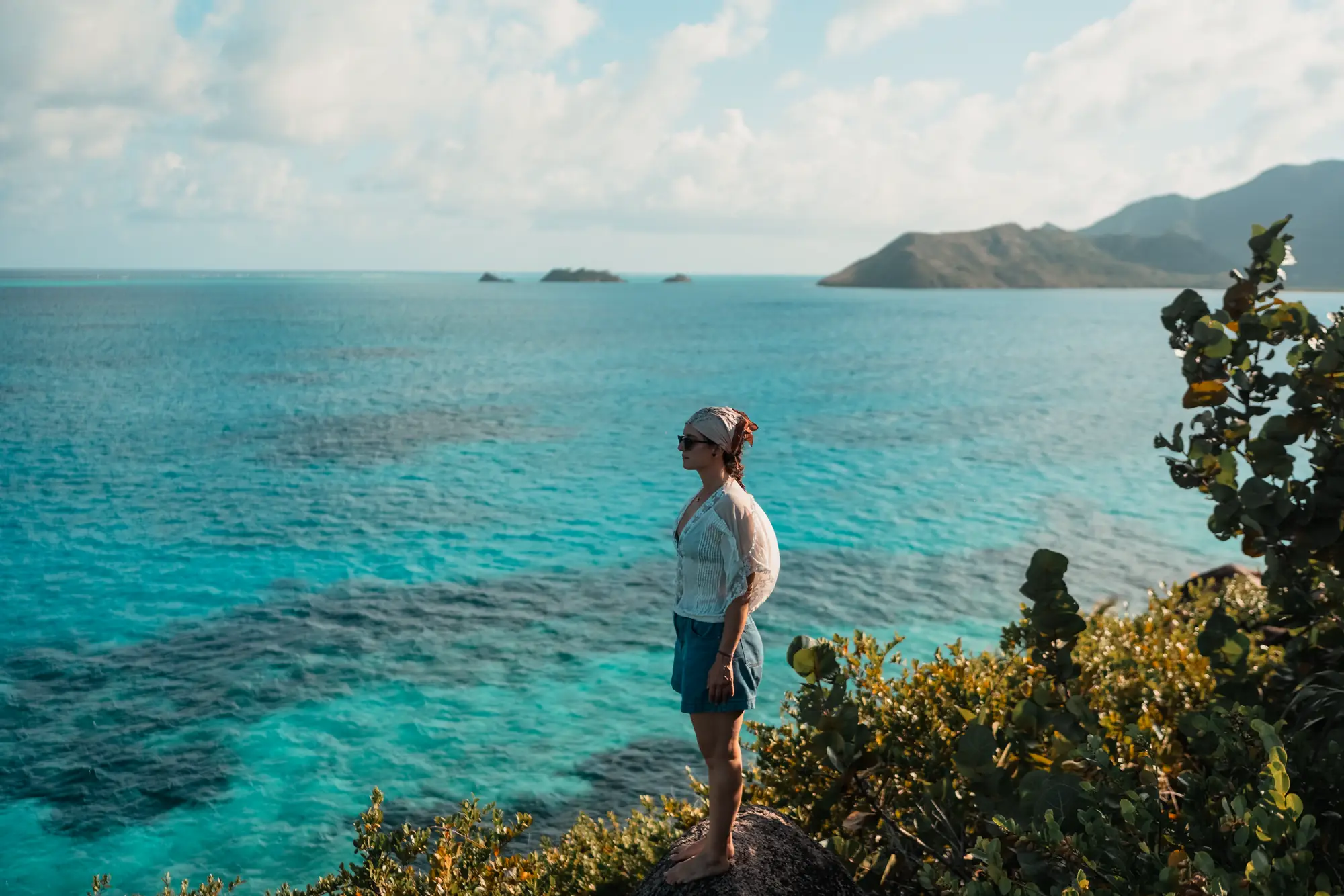 A traveller on a clifftop above turquoise Caribbean water