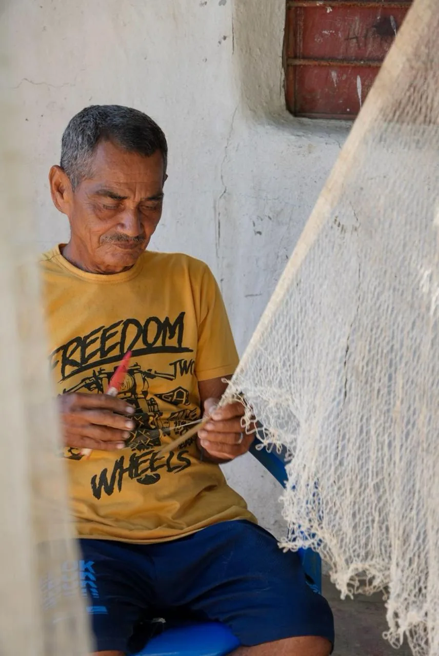 An artisan weaving a traditional fishing net
