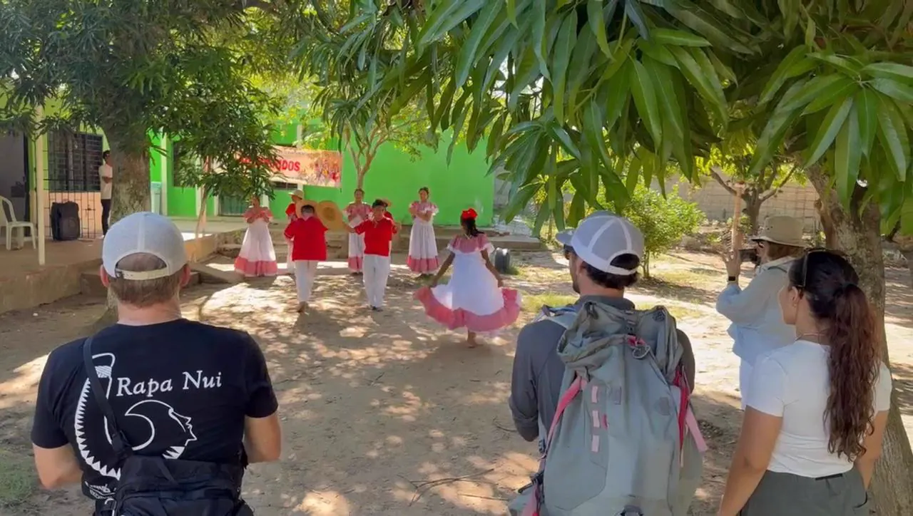 Children in traditional dress dancing cumbia under the trees of the schoolyard