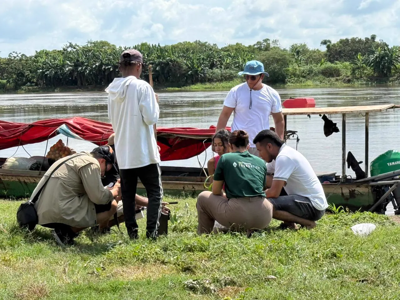Fishermen and team members talking on the riverbank beside their canoes